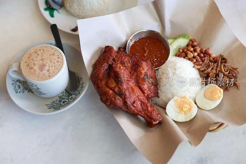 马来西亚的传统食物“Nasi lemak”，有炸鸡和一杯塔克茶。